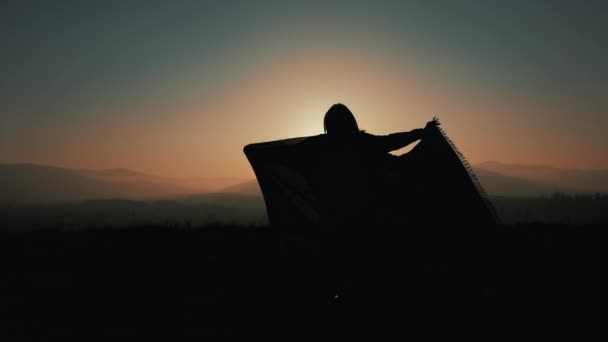 Silhouet van een mooie jonge vrouw met een pareo in haar handen in de bergen. Slow-motion. Het concept van rust, vrijheid, gemak, succes. Zonsondergang — Stockvideo