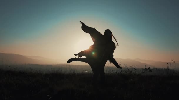 Silhouette di giovane coppia innamorata in vacanza godendo le montagne. Un uomo attraente sta portando la ragazza sulle spalle e la fa girare. Divertirsi — Video Stock