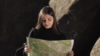 Dikey video. Dağlara yolculuk. Uzun yürüyüşe çıkan kimse kadın kayanın tepesinde eski harita ayakta tutar. Turist güzel dağlarında seyahat eder. Dikey video kullanıma hazır