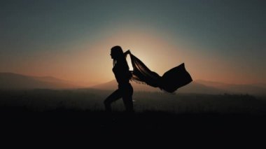 Onun elinde bir pareo ile dağlarda çalışan güzel bir genç kadın silüeti. Ağır çekim. Özgürlük, kolaylığı, başarı, geri kalan kavramı. Günbatımı