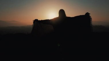 Onun elinde bir pareo ile dağlarda çalışan güzel bir genç kadın silüeti. Ağır çekim. Özgürlük, kolaylığı, başarı, geri kalan kavramı. Günbatımı