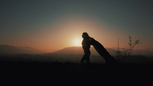 Silhouette einer schönen jungen Frau, die mit einem Pareo in der Hand durch die Berge läuft. Zeitlupe. das Konzept der Freiheit, Leichtigkeit, Erfolg, Ruhe. Sonnenuntergang — Stockvideo