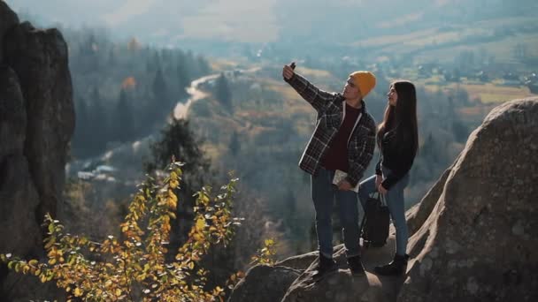 Pasangan muda jatuh cinta berdiri di batu dan mengambil potret selfie. Pria dan wanita mengunjungi atraksi turis terkenal — Stok Video
