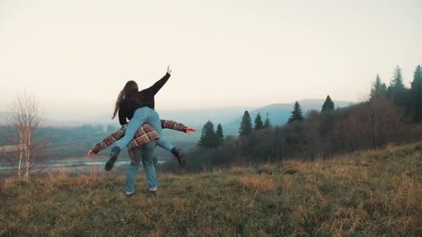 Jeune couple amoureux en vacances profitant des montagnes. Un homme séduisant porte sa copine sur ses épaules et la tourbillonne. S'amuser — Video