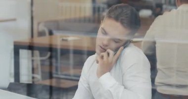 İş sırasında camsı kafede dizüstü bakarak onun Not defteri bilgileri yazma smartphone ile genç iş adamı. Ağır çekim, öğle yemeği zamanı