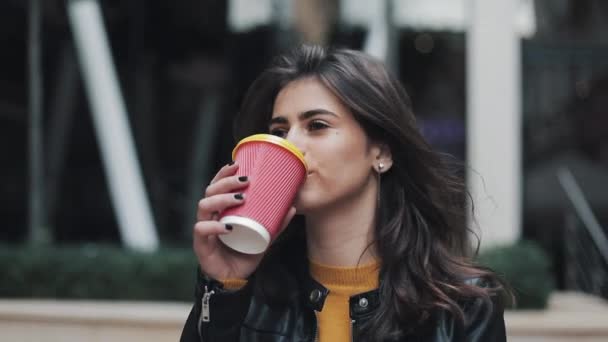 Giovane bella donna che beve caffè e cammina per strada vicino al centro commerciale — Video Stock