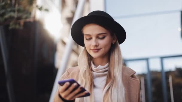 Señora de negocios en sombrero negro enviando mensaje de voz de audio en el teléfono celular al aire libre hablando con el asistente móvil. Chica usando el reconocimiento de voz del teléfono inteligente, dicta pensamientos, mensaje de marcación de voz — Vídeos de Stock