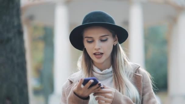 Señora de negocios en sombrero negro enviando mensaje de voz de audio en el teléfono celular al aire libre hablando con el asistente móvil. Chica usando el reconocimiento de voz del teléfono inteligente, dicta pensamientos, mensaje de marcación de voz — Vídeo de stock