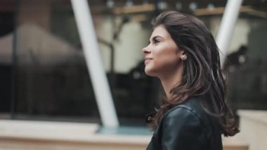 Deri ceketli genç ve güzel kadın iş merkezine yakın yürüyor. Kız saç güzelliği burada giderir.