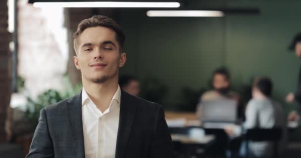 Портрет молодого успешного бизнесмена в напряженном офисе. Красивый работник смотрит в камеру и улыбается. Бизнес, финансы, основатель, концепция успеха — стоковое видео