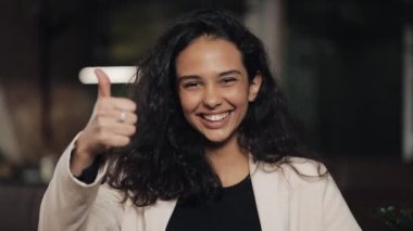 Güzel genç kadın rahat kafede başparmak yukarı ve başparmak aşağı ayakta gösterir. Başparmak işareti iş yerinde genç kız ile aşağı yukarı