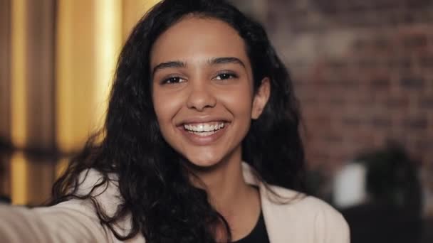 Aantrekkelijke jonge vrouw video chatting, spioneren. Vrouw zwaaien naar de camera tijdens de vergadering in het gezellige café. Close-up — Stockvideo