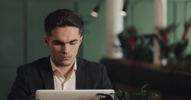 累了年轻的商人坐在咖啡馆里的一张桌子上 在一台笔记本电脑上工作 自由职业者 疲惫的商人概念 — 图库视频影像