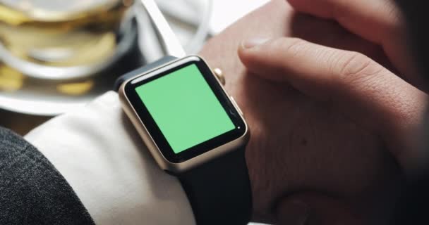 Közelről üzleti ember kezét a smartwatch zöld képernyő chroma key. Bekapcsolás, megérinti, és jelet ad tekerő. Háttérben hangulatos kávézó — Stock videók