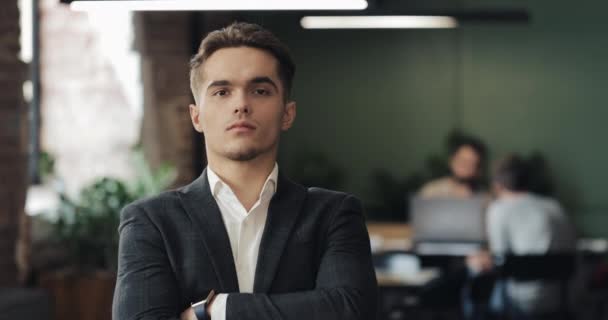 Retrato de un joven empresario exitoso en una oficina ocupada. Hombre guapo empleado mirando a la cámara y haciendo pulgares hacia arriba en el lugar de co-trabajo — Vídeos de Stock