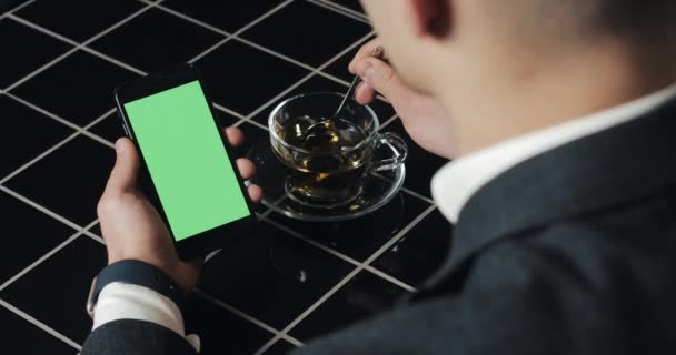 Jovem empresário usar smarthpone com touchpad greenscreen e gesto de perto no café. Cara segurando celular, tocando e rolando pelas páginas de navegação e ler notícias — Vídeo de Stock