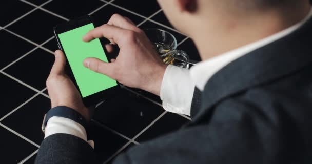 Νεαρός επιχειρηματίας χρήση smarthpone με greenscreen touchpad και χειρονομώ κοντινό καφέ. Guy κρατά κινητής τηλεφωνίας, υποκλοπή και την κύλιση στις σελίδες περιήγησης και διαβάστε ειδήσεις — Αρχείο Βίντεο