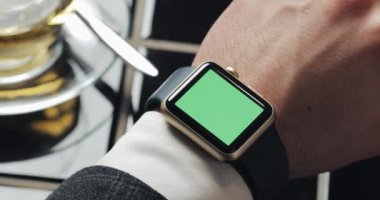 İş adamı elinde smartwatch yeşil ekran chroma anahtar ile kapatın. Arka planda rahat kafe