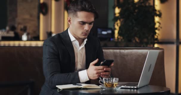 Jonge zakenman in café werkt. Freelancer met smartphone en laptop. Succesvolle busines, It, Freelancer concept. — Stockvideo