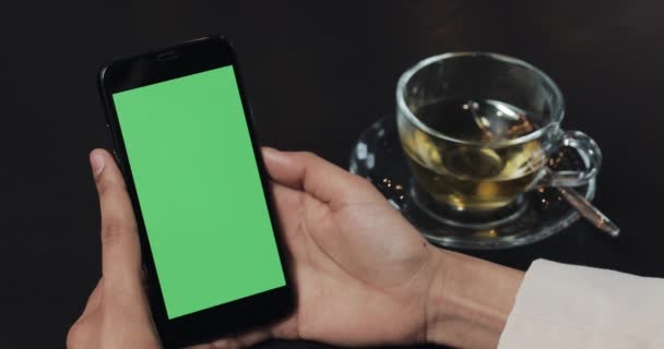 Giovane donna è in possesso di smartphone con schermo verde al Cozy Cafe. Stile di vita casuale — Video Stock