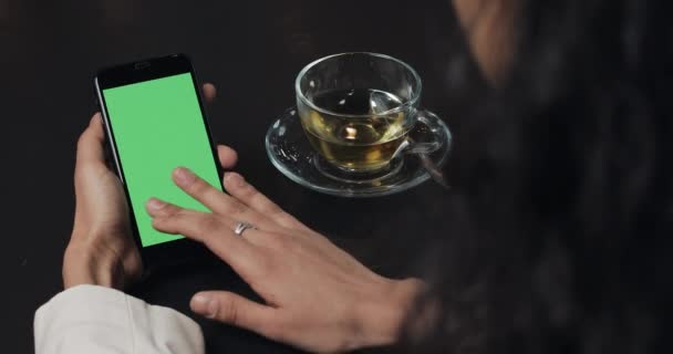 Joven mujer de negocios utilizar el teléfono inteligente con pantalla verde touchpad y el gesto de cerca en la cafetería. Chica sosteniendo el celular, deslizando por las páginas de navegación y leer noticias — Vídeo de stock