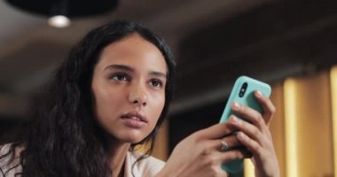 Sesli iletiyi dinleme smartphone ile mutlu bilen bir kadın. Kız kafede, iş kadını modern ofis oturma mobil ses denetimi kullanın