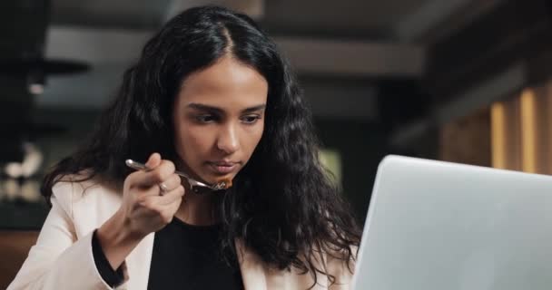 Business woman sitting with a laptop in the cafe and eating dinner with a cup of tea on the table. Eating lunch at work desk — Stock Video