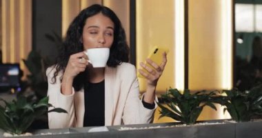 Kafede Smartphone kullanan yorgun iş kadın. Modern coworking ve kahve içme oturan kız