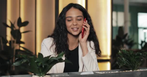 Jovem mulher de negócios feliz falando ao telefone enquanto está sentado no café. Ela está sorrindo e bebendo café. Menina bonita ter conversa casual no telefone móvel — Vídeo de Stock