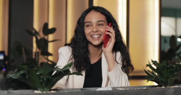 Joven mujer de negocios feliz hablando por teléfono mientras está sentado en la cafetería. Ella sonríe. Hermosa chica teniendo conversación casual en el teléfono móvil — Vídeo de stock