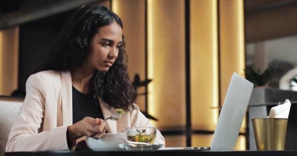 Geschäftsfrau sitzt mit Laptop im Café und isst mit einer Tasse Tee auf dem Tisch zu Abend. Mittagessen am Schreibtisch — Stockvideo