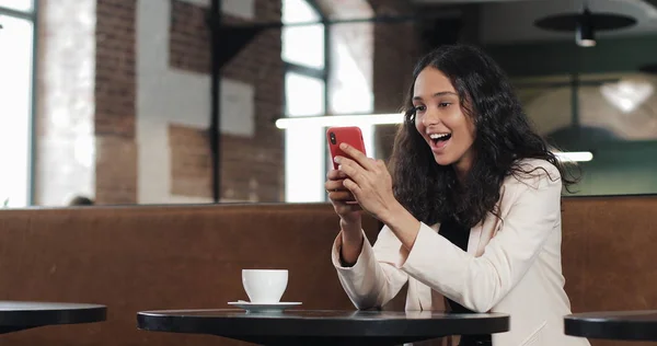 Modern ofisinde oturan Smartphone cep telefonu ile App kullanarak iş kadını. İyi haber smartphone sahip pembe elbiseli güzel casual kadın profesyonel