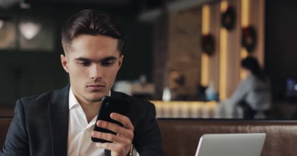 Ung affärsman arbetar på smartphone sitter i mysiga café — Stockvideo