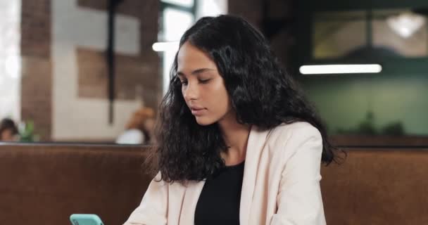 Portrait of successful business woman with smartphone in her hand looking at the camera and smiling while working in the urban office. Close up — Stock Video