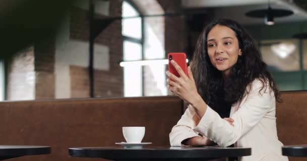 Kobieta biznesu szczęśliwy rozmowy na telefon o rozmowy przez czat wideo konferencji w przytulnej kawiarni. Kobieta biznesu za pomocą smartphone aplikacji na smartfon uśmiecha się zadowolony — Wideo stockowe