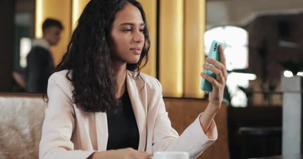 Mulher de negócios jovem bonita usando smartphone sentado no café acolhedor — Vídeo de Stock