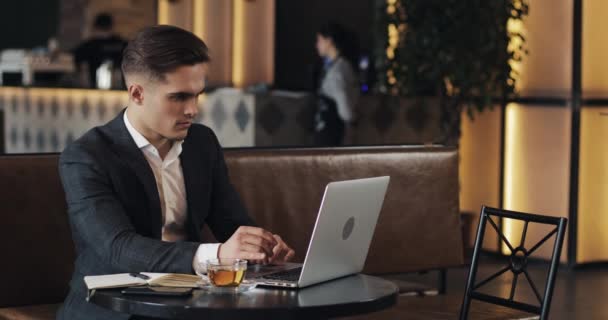 Hombre de negocios sonriente usando computadora portátil sentada en la mesa de la cafetería — Vídeos de Stock