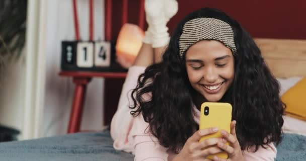 Chica joven feliz usando el teléfono en casa acostado en la cama. Mensajes de texto de chat. Comunicación en línea — Vídeos de Stock