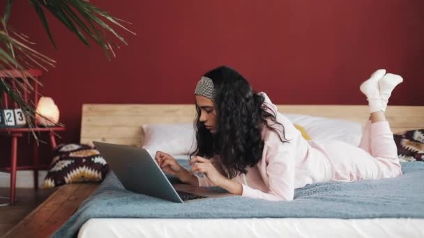 Une femme se fâche et s'énerve après avoir reçu un message sur son ordinateur portatif. Elle est allongée sur le lit. — Video