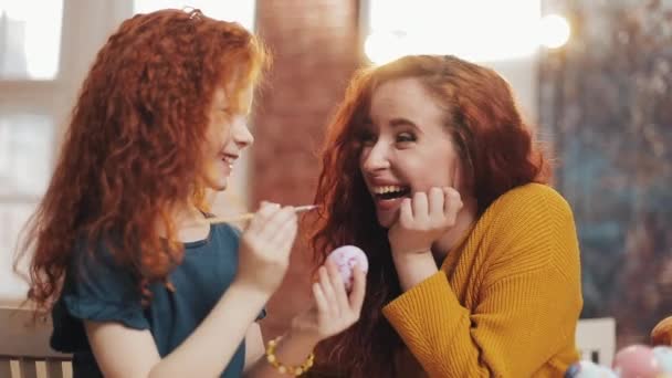 A mother and her daughter painting Easter eggs in cozy kitchen. They laughing and have fun. Happy family preparing for Easter. Happy easter — Stock Video