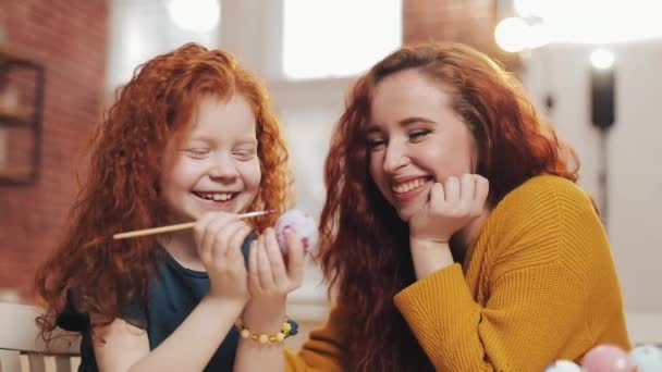 Une mère et sa fille peignent des œufs de Pâques dans une cuisine confortable. Ils rient et s'amusent. Bonne famille se préparant pour Pâques. Joyeuse Pâques — Video