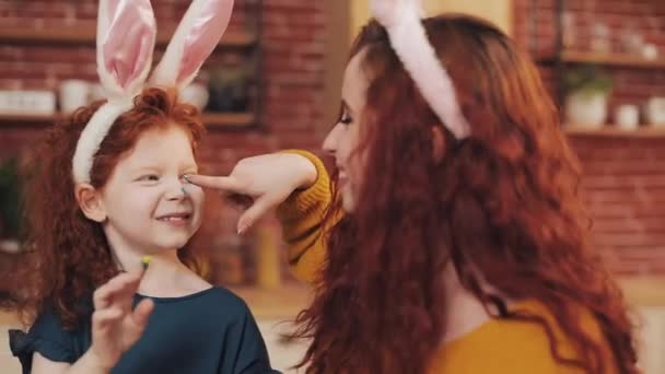 ハッピー イースター。若い母親と彼女の小さな娘は、お互い卵と顔をペイントします。家族のジョーク — ストック動画
