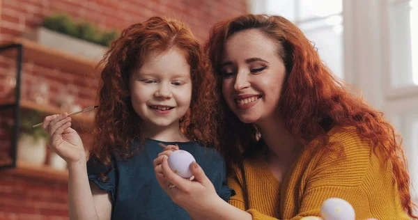 Bir anne ve kızı sıcak mutfağa paskalya yumurtası boyuyor. Gülüyorlar ve eğleniyorlar. Mutlu aile Paskalya için hazırlanıyor. Mutlu Paskalyalar