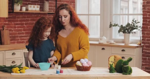 Mama i jej córeczka przygotowują się na Wielkanoc. Szczęśliwa rodzina przygotowuje malowanie pisanek w przytulnej kuchni — Wideo stockowe