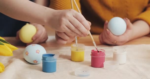 Primer plano de las manos madre e hija colorear huevos de Pascua con colores y cepillo. Huevos coloridos de Pascua. Preparación de la Pascua — Vídeos de Stock