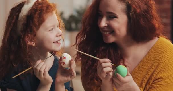 Happy easter. Mother and her little daughter painting eggs. Happy family preparing for Easter. They wearing bunny ears — Stock Video