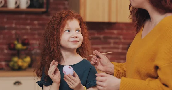 Mutlu paskalyalar. Anne kızı yumurta boyama öğretir. Mutlu bir aile Paskalya için hazırlanıyor. Onlar tavşan kulakları giyiyor