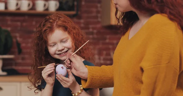 Mutlu paskalyalar. Anne kızı yumurta boyama öğretir. Mutlu bir aile Paskalya için hazırlanıyor. Onlar tavşan kulakları giyiyor