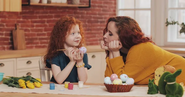 Annem ve küçük kızı Paskalya için hazırlanıyorlar. Paskalya yumurtalarını sıcacık mutfakta boyayan küçük bir kız. Gülümseyen anne kızına bakar.