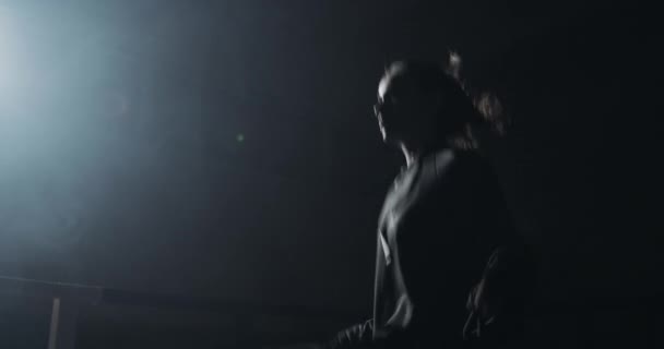 Μια νεαρή γυναίκα που πηδάει σχοινί σε ένα σκοτεινό δαχτυλίδι. Σιλουέτα. Ιδέα πυγμαχίας — Αρχείο Βίντεο